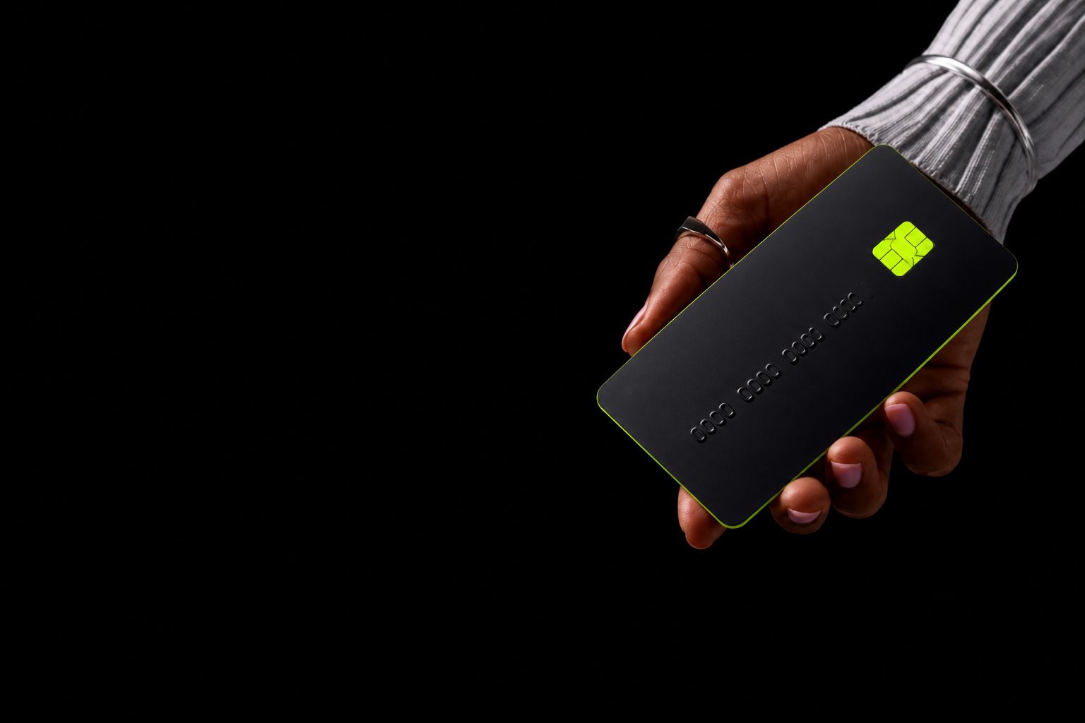 A hand holding a black credit card with a neon chip